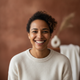 Close-up portrait of a smiling woman, mid-30s, with a warm, blurred background, conveying trust and happiness.